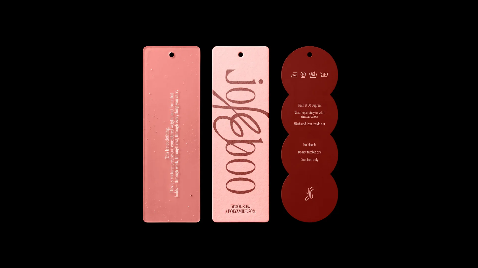 Three swing tags on black: a coral manifesto tag, a pink tag with the wordmark running off both edges, and a garnet care tag made of four circles
